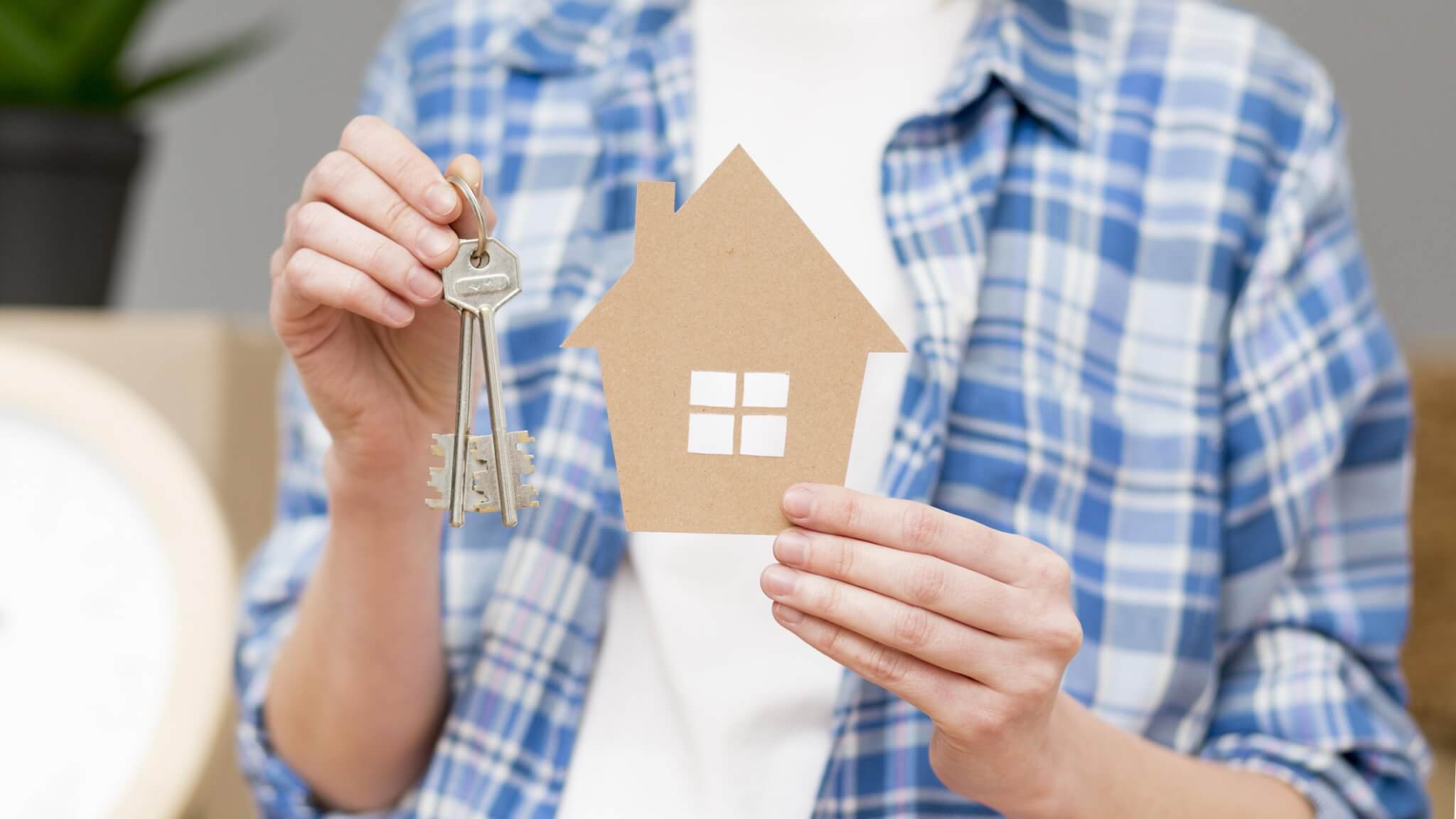 manos sosteniendo una llaves y una casa madera