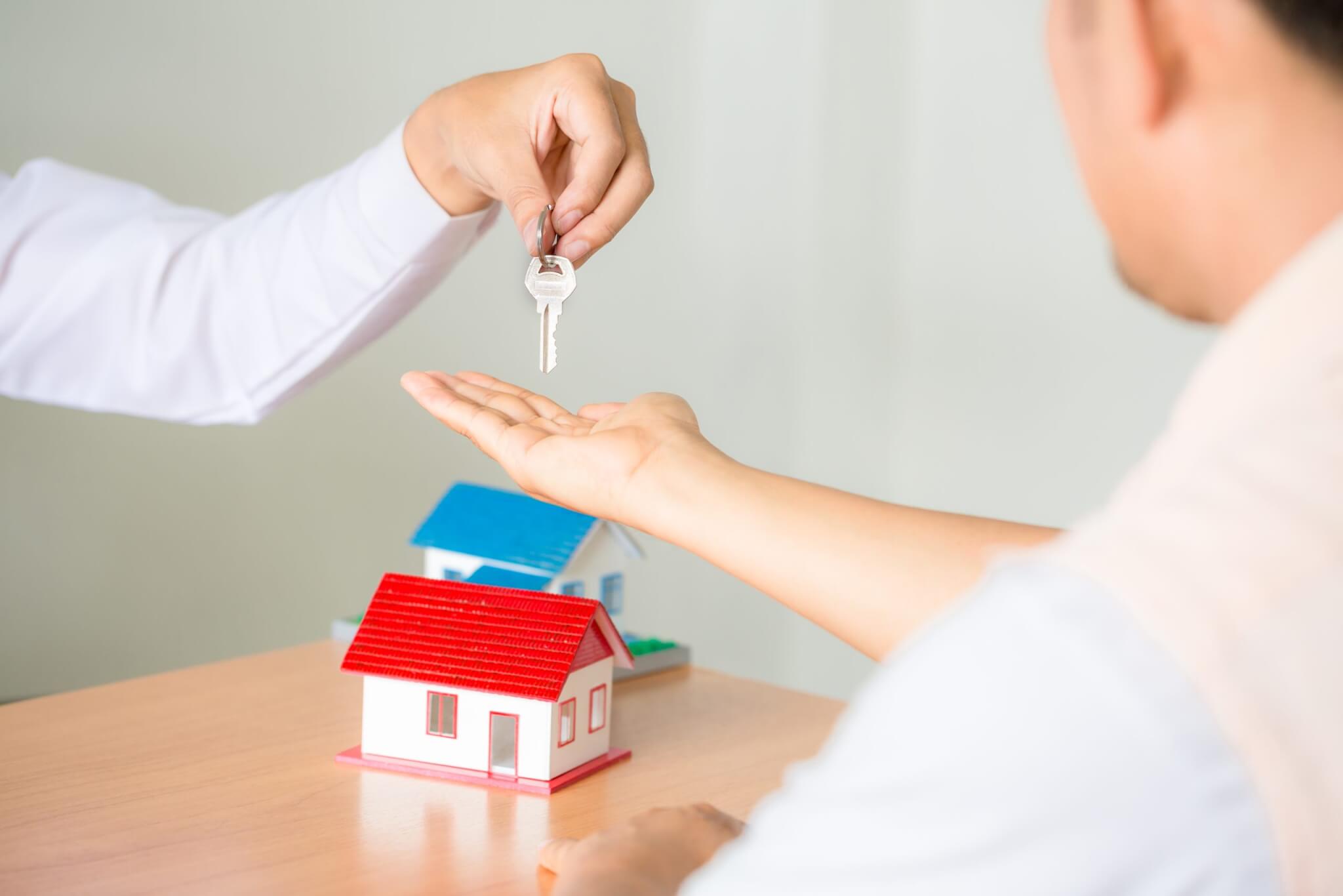 Gestor de ventas inmobiliarias entregando las llaves al cliente tras la firma del contrato de arrendamiento de compraventa